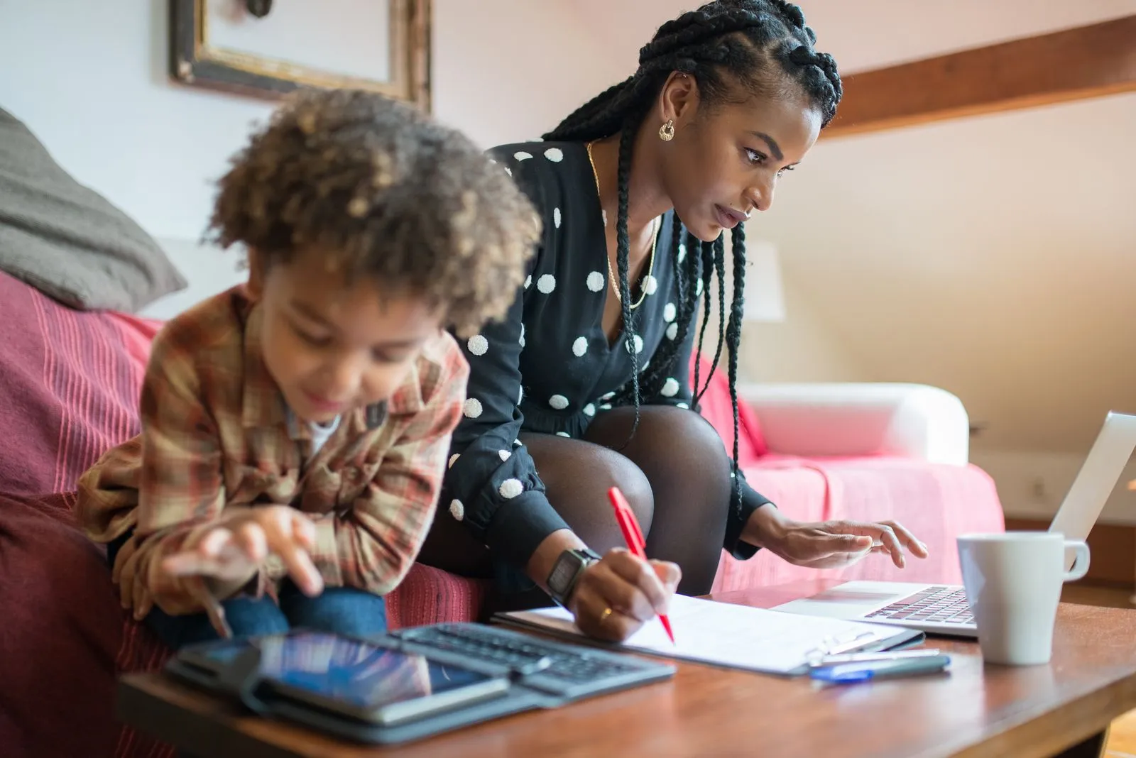 Mamá trabajando en su laptop mientras su peque juega al lado